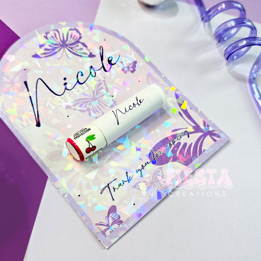 Personalized holographic lip balm favor with 'Nicole' on arched card for 13th birthday, butterfly design.
Custom lip balm party favor featuring a shimmering cold-laminated card for special event thank you gifts.
Luxury custom lip balm on personalized card, 'sealed for your protection' cherry flavor, perfect for teen parties.